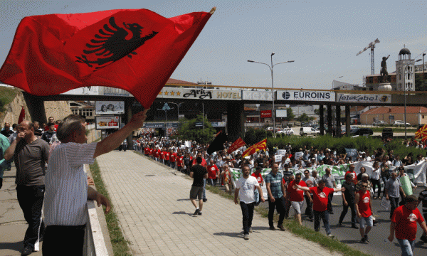 Flamuri shqiptar po valëvitet në mbështetje të protestës së opozitës gjatë marshimit drejt kryeministrisë në Shkup të Maqedonisë më 17 maj 2015. Mes protestuesve dallohen flamuj të bashkësive të ndryshme etnike në një shfaqje të rrallë solidariteti në një shoqëri që prej dekadash ka jetuar e segreguar. (AP Photo/Boris Grdanoski)