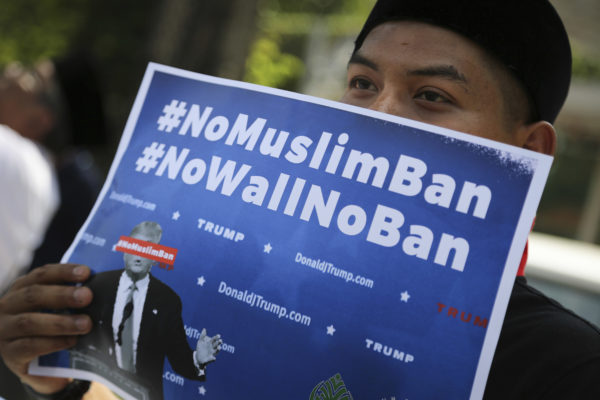 A Muslim protesters holds a placard while demonstrating against U.S. President Trump's immigration ban outside the U.S. Embassy in Kuala Lumpur, Malaysia, on Friday, Feb. 3, 2017. Trump's order temporarily halted the entire U.S. refugee program and banned all entries from seven Muslim-majority nations for 90 days. (AP Photo/Vincent Thian)